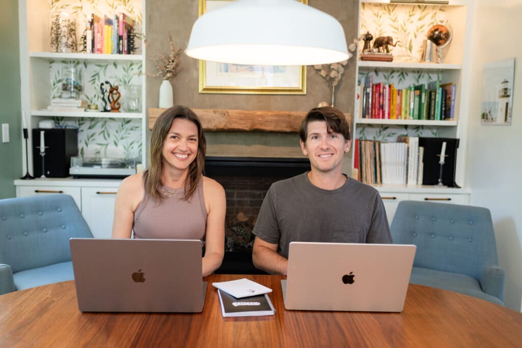 Nic and Brianna smiling at their dining table with laptops